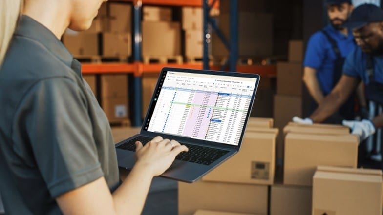 manager in warehouse using laptop